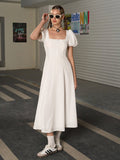 Full body shot of a woman in a white puff sleeve midi dress, adjusting sunglasses.