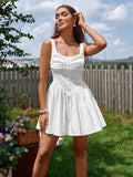 Woman wearing a white sleeveless ruched bodice fit and flare dress with a gathered skirt and square neckline, standing outdoors.
