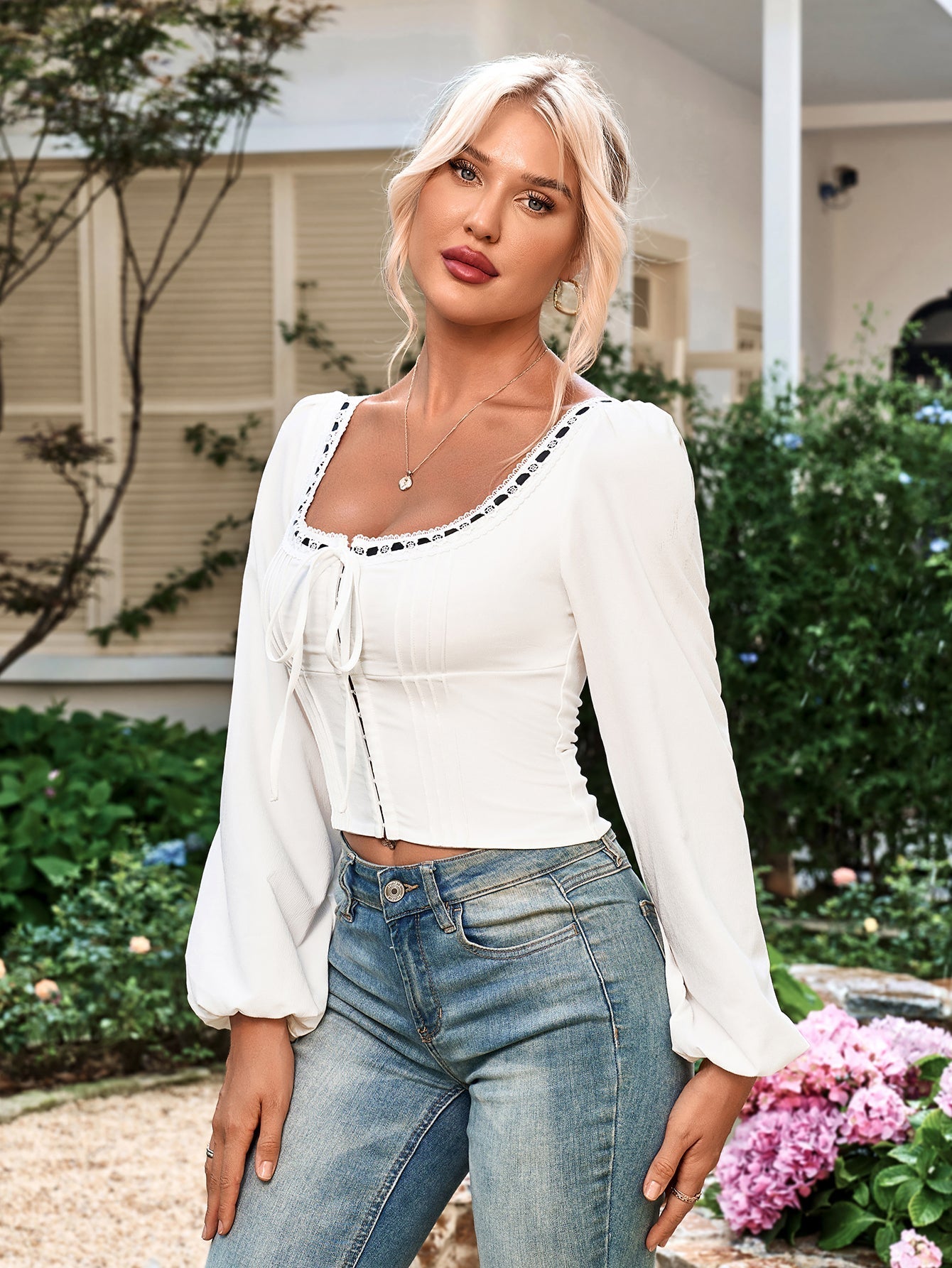 Close-up of a woman wearing a white cropped top with a decorative square neckline and puff sleeves.