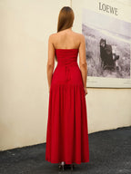 Back view of a woman in a red strapless maxi dress with a lace-up detail