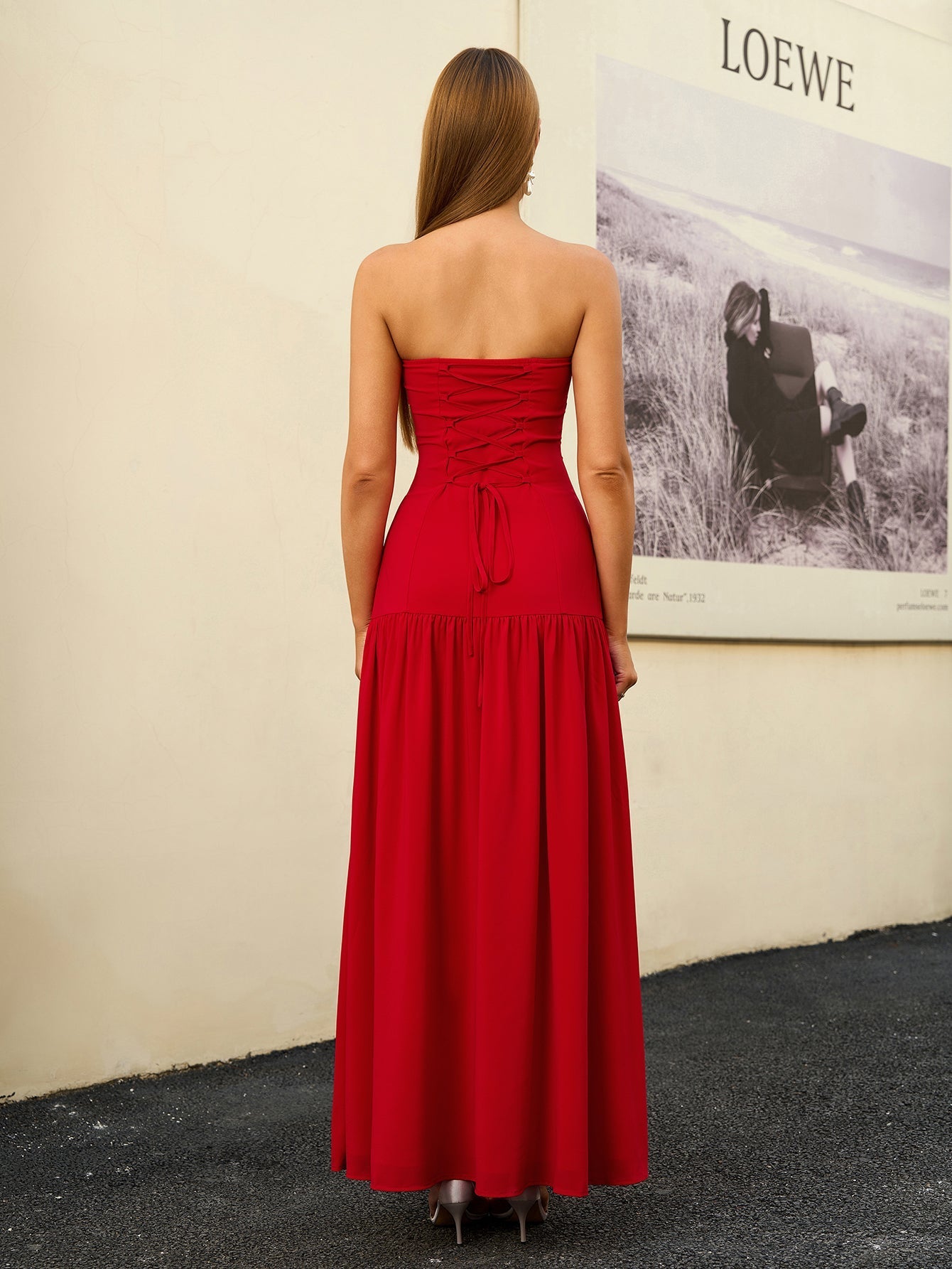 Back view of a woman in a red strapless maxi dress with a lace-up detail