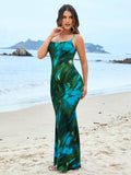 Woman posing in a green and blue tie-dye spaghetti strap mermaid maxi dress on the beach