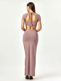 Back view of a woman in a mauve two-piece set featuring a cropped top with a tie closure and a high slit maxi skirt.