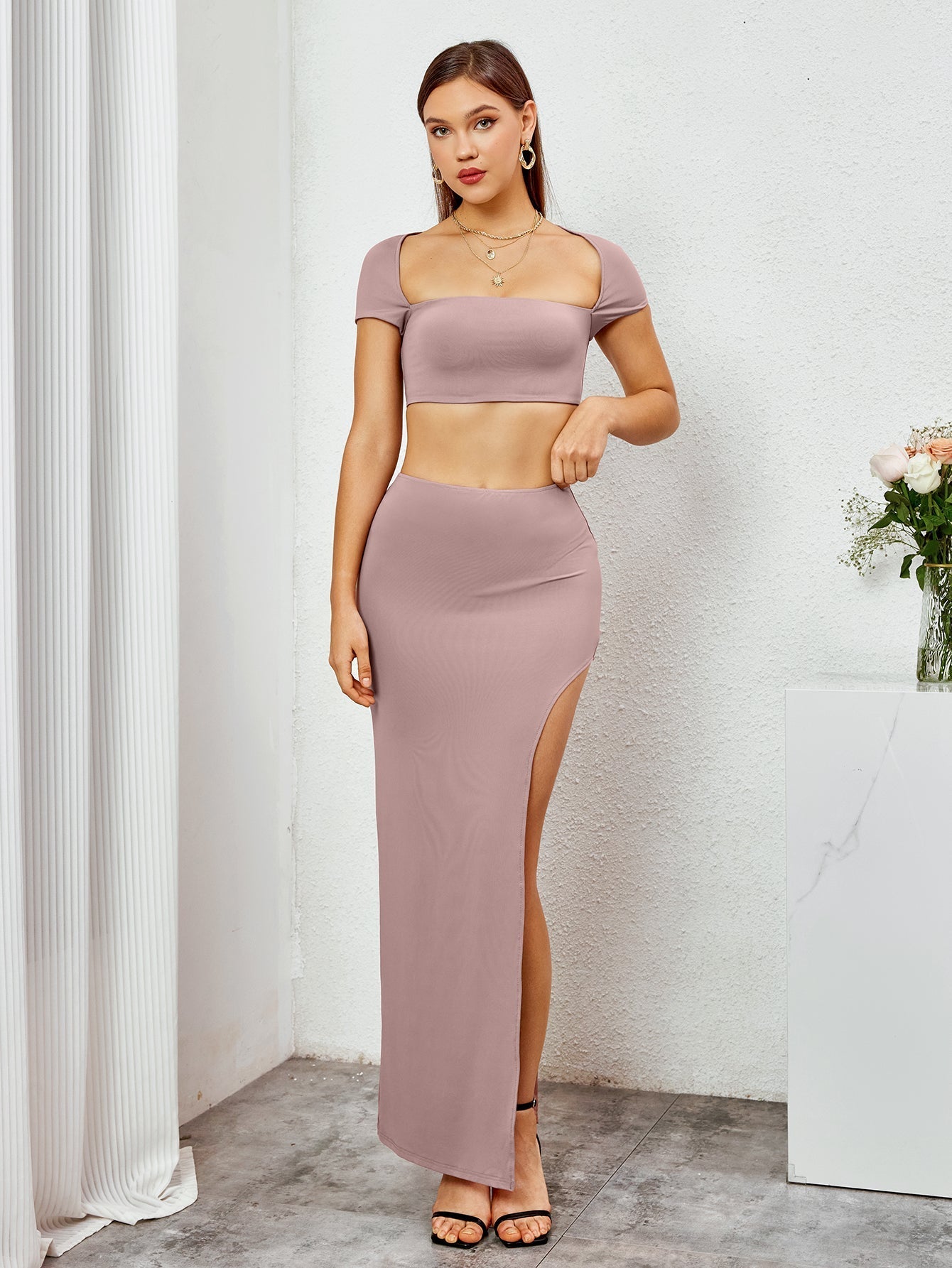 Woman standing in a mauve cropped top and high slit maxi skirt, showing the outfit's details.