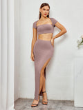 Woman posing in a mauve two-piece set with a cropped top and high slit maxi skirt.