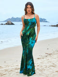 Woman standing on the beach in a green and blue tie-dye spaghetti strap mermaid maxi dress