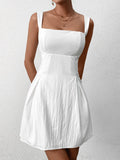 Front view of a woman in a white fit and flare dress with a square neckline.
