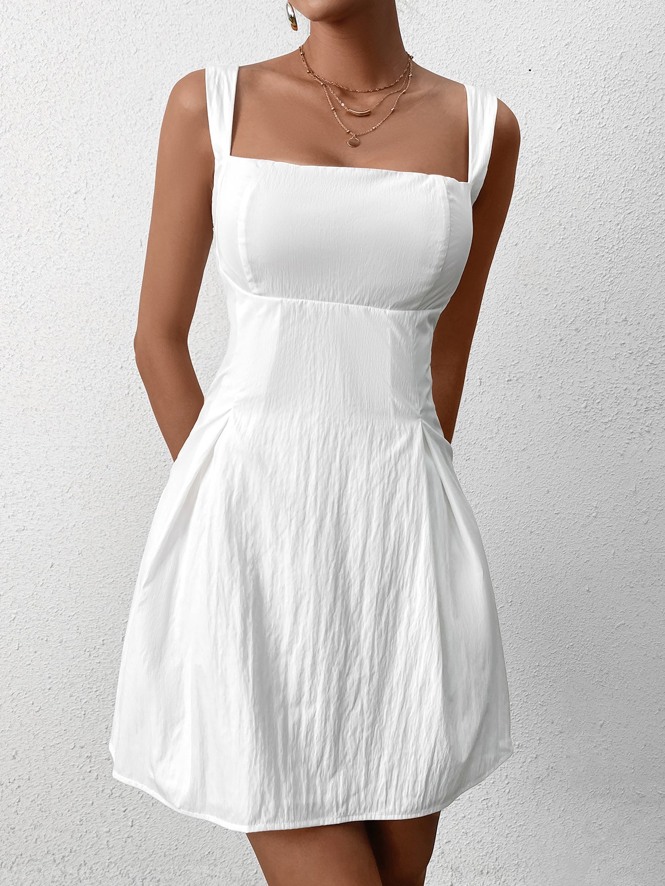 Front view of a woman in a white fit and flare dress with a square neckline.