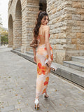 Back view of a woman in a long, floral print dress with ruched detailing and spaghetti straps.