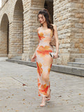 A woman walks forward wearing a flowing floral print maxi dress.