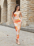 Full-length view of a woman posing in a light pink maxi dress with an orange and red floral print.