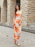 Woman wearing a long, sleeveless floral print dress with spaghetti straps and a square neckline.