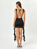 Back view of a woman in a black sleeveless bodycon mini dress with an open back and tie closure.