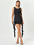 Woman wearing a black sleeveless bodycon mini dress with ruffle details and rose embellishments.