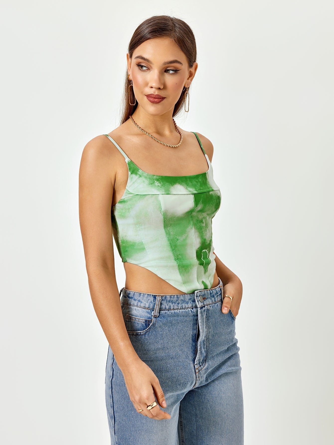 Side view of a woman in a green tie-dye print cropped corset top with adjustable spaghetti straps and a square neckline.
