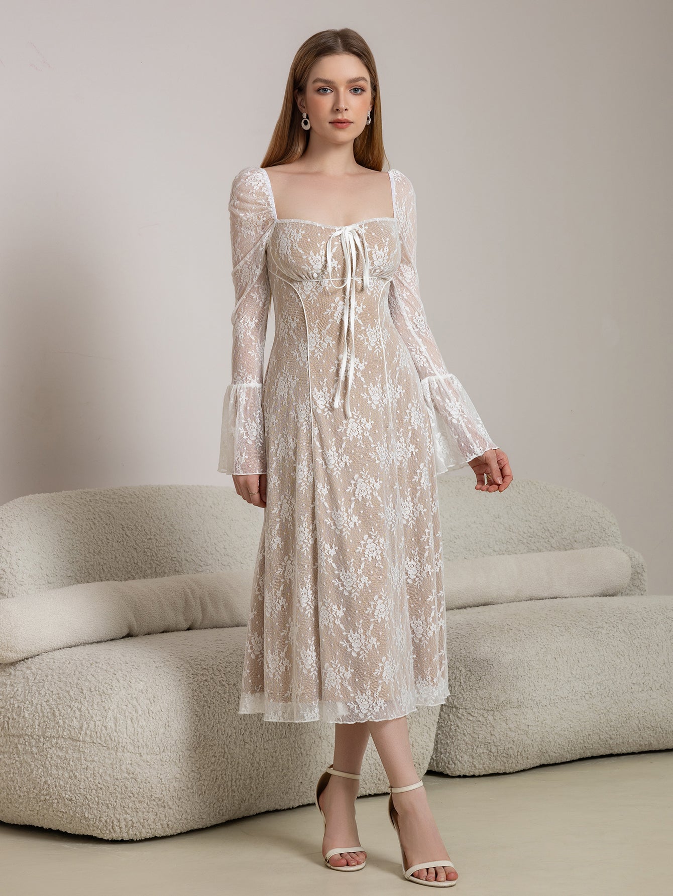 Model posing in a white lace midi dress with bell sleeves and a tie-front detail.