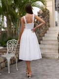 Rear view of a woman in a white eyelet midi dress with a smocked back panel and ruffled straps.