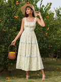 Full body shot of a woman modeling a yellow floral print A-line midi dress with tiered skirt and ruffle trim.