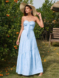 Woman wearing a light blue floral print strapless maxi dress and a wide-brimmed straw hat, posing outdoors.