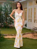 Woman wearing a white maxi slip dress with a yellow floral print, featuring spaghetti straps and a V-neckline, posing outdoors.