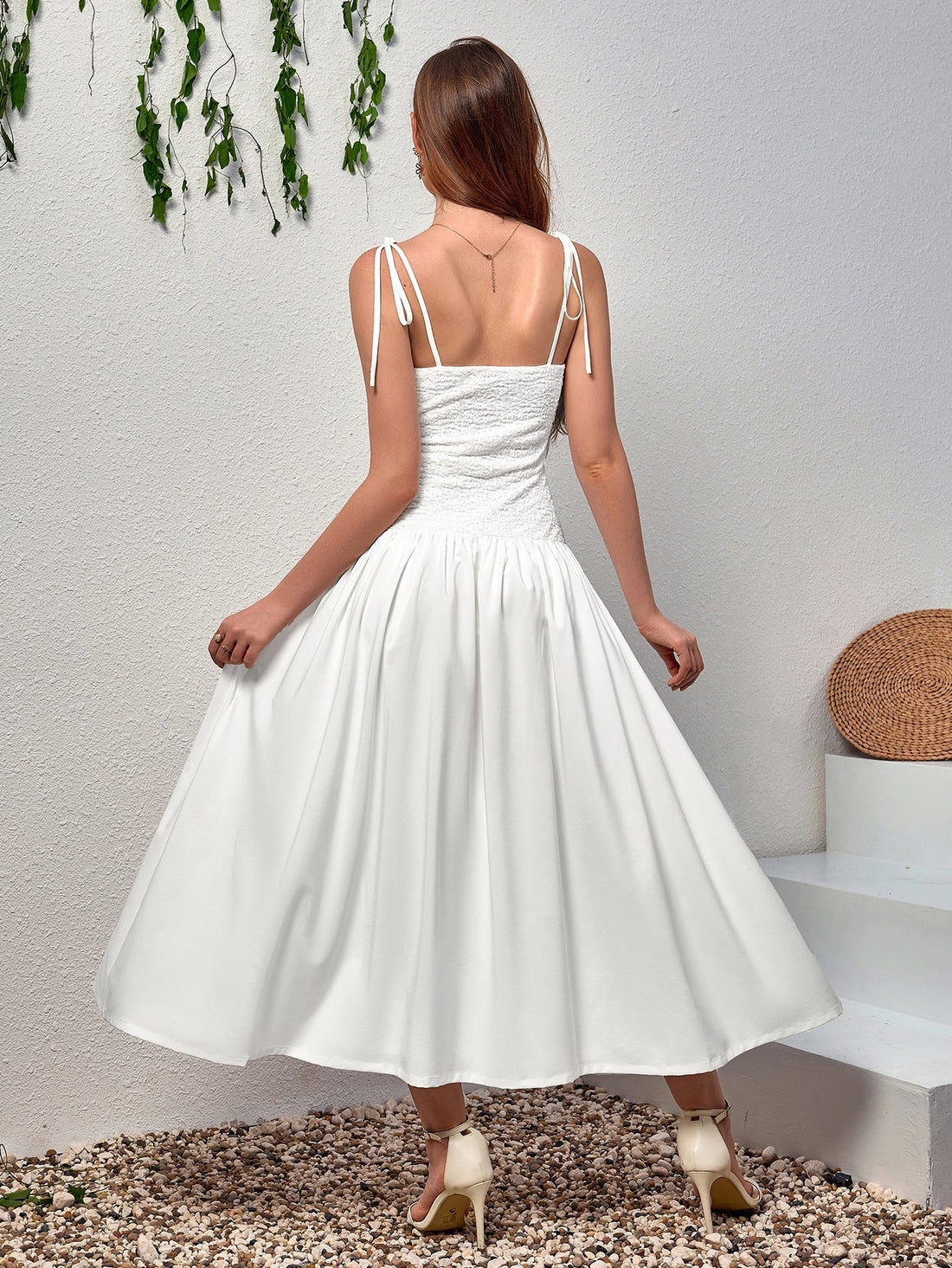 Woman wearing a white midi dress with a smocked bodice and a flowing skirt
