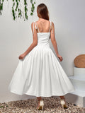 Back view of a woman in a white midi dress with tie shoulder straps and a smocked bodice