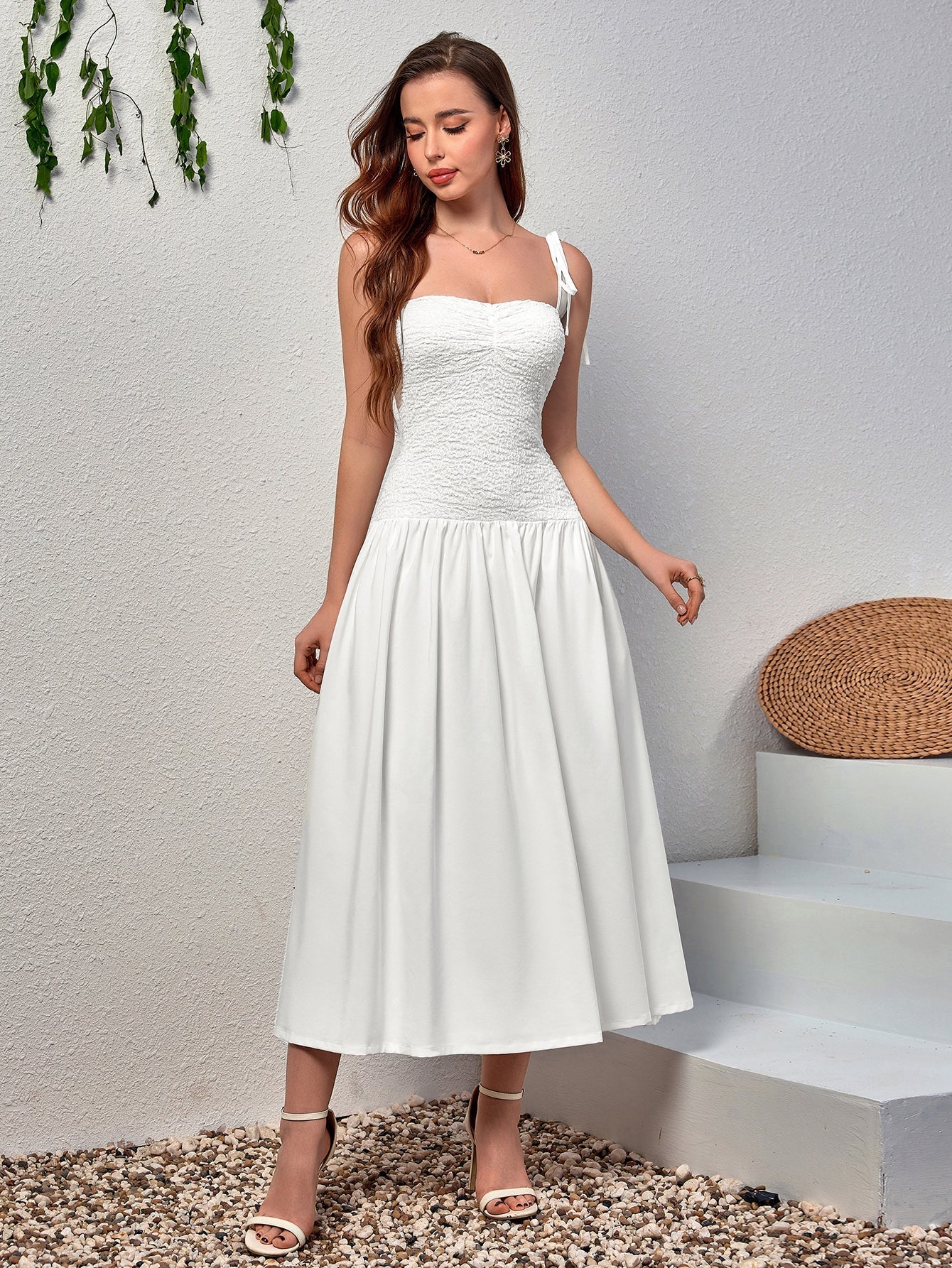 Front view of a woman posing in a white fit and flare midi dress with a sweetheart neckline