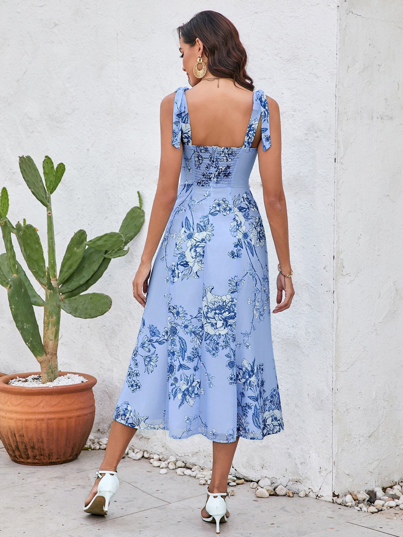 Back view of a woman in a blue floral print midi dress with smocked back.