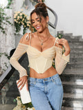 Close-up of a woman wearing a light yellow ruched off-the-shoulder long-sleeve crop top with tie shoulder straps and a pointed hemline, styled with layered necklaces.