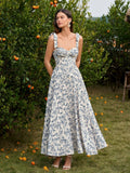 Full body shot of a woman in a floral print midi dress with a sweetheart neckline and tie shoulder straps, standing outdoors.