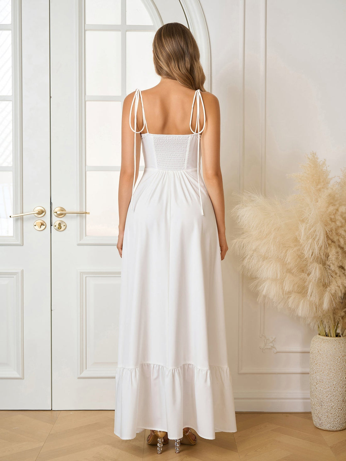 Woman wearing a white sleeveless maxi dress with adjustable tie straps and a ruched bodice.