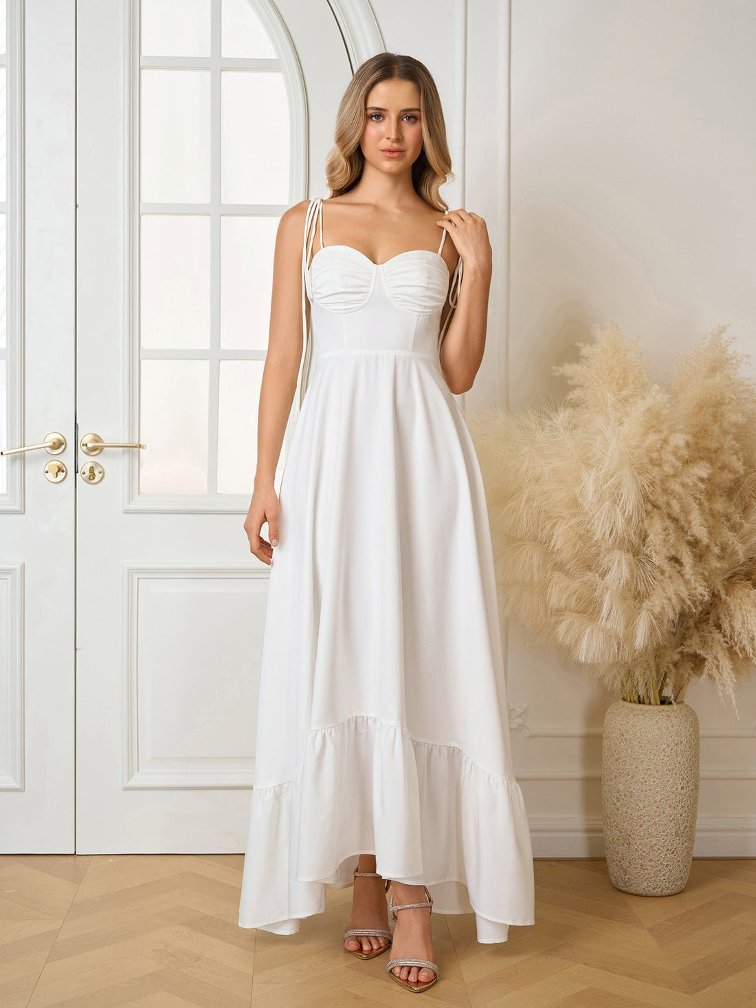 Woman wearing a white sleeveless maxi dress with adjustable tie straps and a ruched bodice.