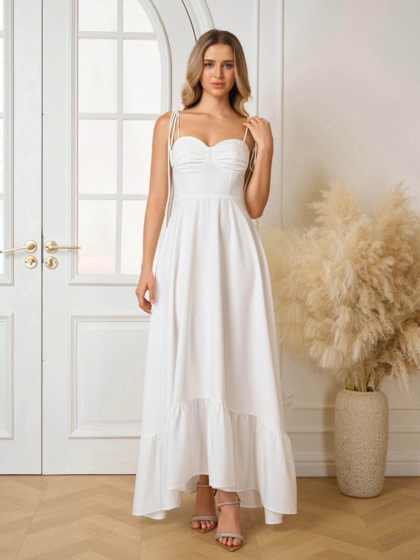 Woman wearing a white sleeveless maxi dress with adjustable tie straps and a ruched bodice.