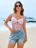 Woman on a beach wearing a pink floral lace cropped camisole with tie straps and blue distressed denim shorts.
