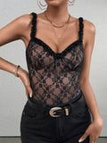 Front view of a woman wearing a black lace camisole with ruffled straps and a bow, paired with black jeans and a belt.