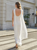 Back view of a woman in a long white sleeveless formal dress with an open back and flowing cape detail.