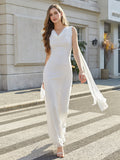 Woman in a long white sleeveless formal dress with a draped cowl neckline and flowing cape detail walking across a crosswalk.
