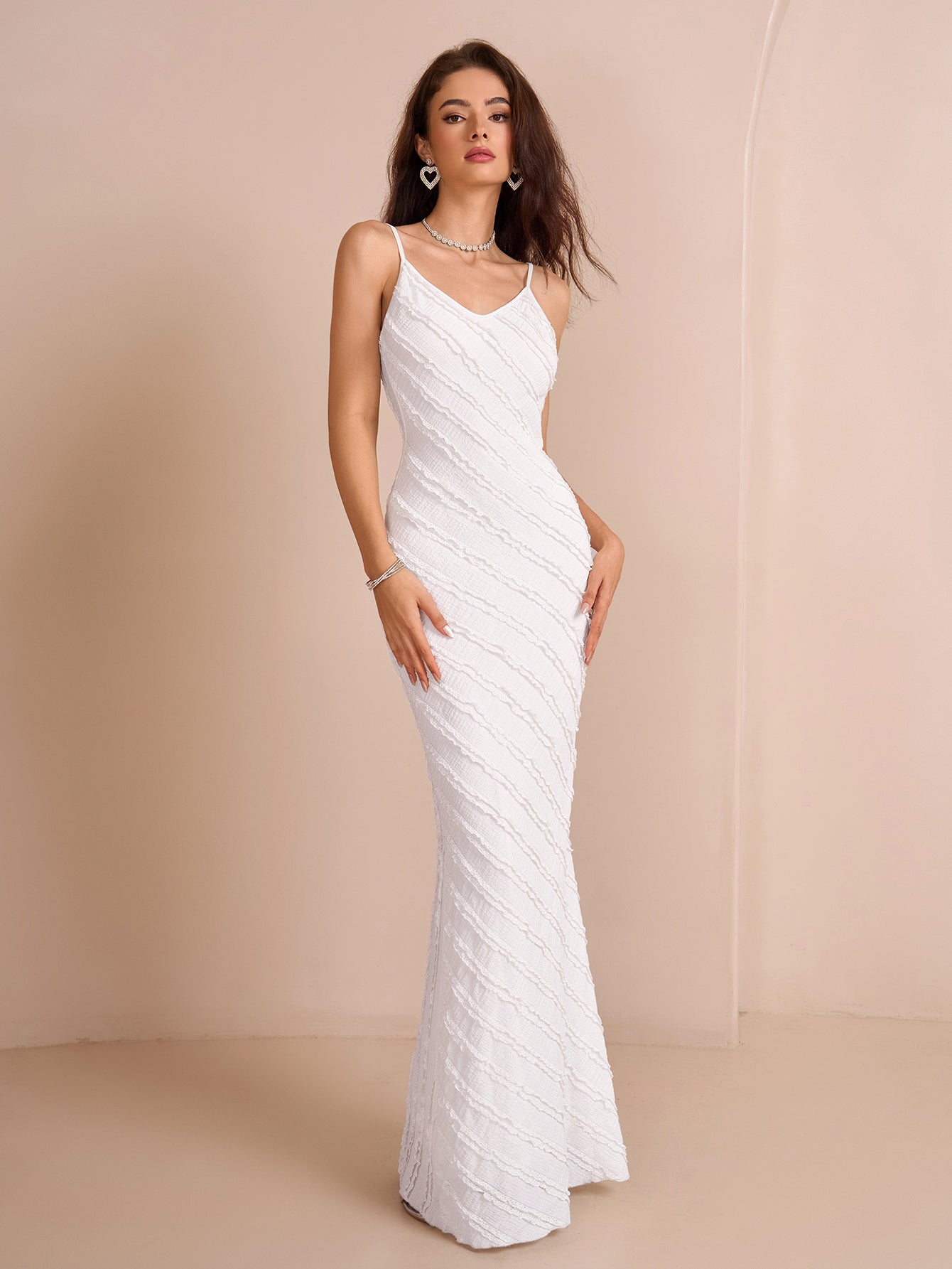 Full body shot of a woman in a white textured mermaid gown with spaghetti straps.