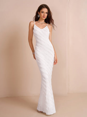 Woman wearing a white floor-length mermaid dress with spaghetti straps and diagonal textured detailing.