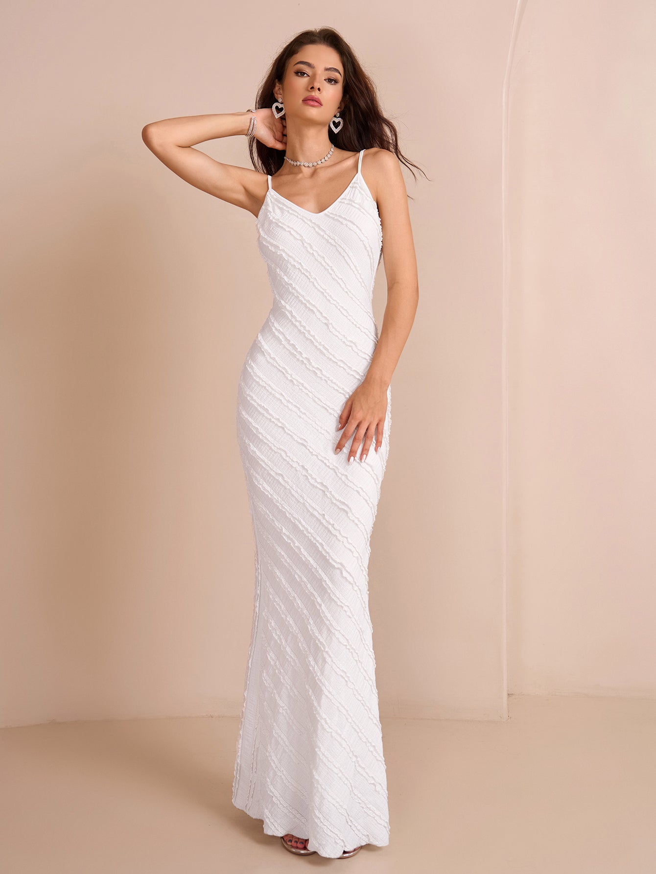 Woman posing in a white textured mermaid dress with a v-neckline and spaghetti straps.