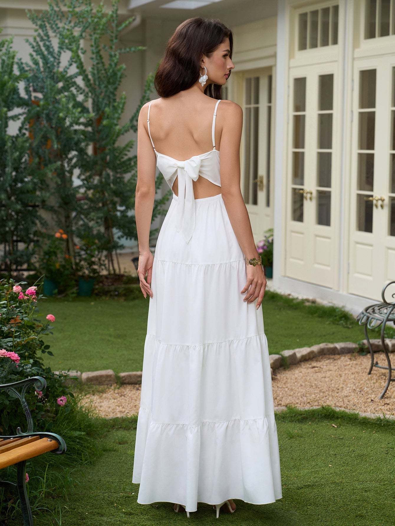 Back view of a woman in a white tiered maxi dress with a bow tie detail at the open back.