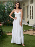 Woman wearing a white tiered maxi dress with spaghetti straps and a plunging neckline, posing outdoors in a garden.