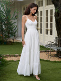Full body shot of a woman in a white tiered maxi dress with spaghetti straps, standing in a garden.