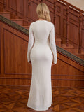 Back view of a woman in a white long-sleeved textured knit mermaid gown with a v-neckline and ruching detail, standing on a wooden staircase.