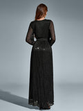 Back view of a woman in a black long-sleeved maxi dress with a v-neck and high slit, adorned with scattered metallic dots.