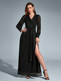 Woman in a black long-sleeved maxi dress with a v-neck and high slit, adorned with scattered metallic dots, posing with one hand on hip.