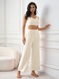 Woman leaning against a wall in a cream-colored loungewear set.