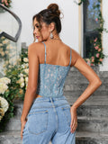 Rear view of a woman in a blue lace corset top with adjustable spaghetti straps and a cropped hem.