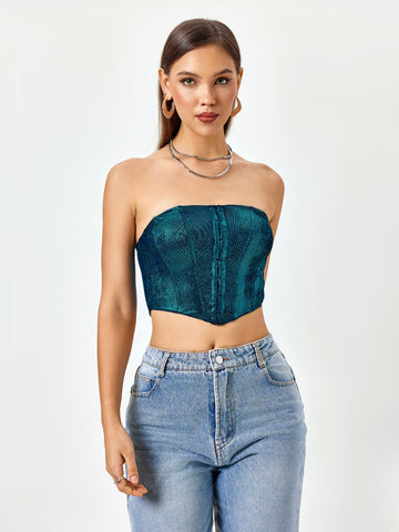 Woman wearing a teal textured metallic strapless corset top and light wash denim jeans
