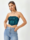 Woman posing with hands in pockets, wearing a teal textured metallic strapless corset top and light wash denim jeans
